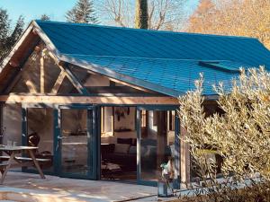 a house with a blue roof and a patio at Le loft Normand avec piscine chauffée in Saint-Antonin-de-Sommaire