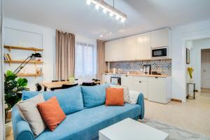 a living room with a blue couch and a kitchen at Modern Italia Apart - 100m Main Square - parking and lift in Wrocław