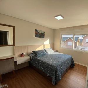 ein Schlafzimmer mit Bett, Schreibtisch und Fenster in der Unterkunft Casa Nova Canela Condominio Fechado 40 in Canela + 17 Fotos