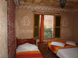 1 dormitorio con 2 camas y ventana en Maison d'Hôte Valentine, en Tinerhir