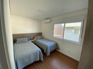 ein kleines Schlafzimmer mit 2 Betten und einem Fenster in der Unterkunft Casa Linda Canela condomínio!!! 39 in Canela