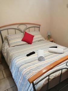 uma cama com uma almofada vermelha e um relógio em Chez Christian em Désertines