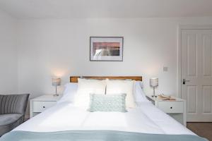 a bedroom with a large white bed and a chair at Pebble Bay Apartment in Deal