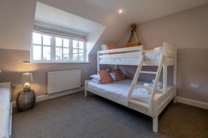 a bedroom with two bunk beds and a window at 1 Sanctuary Court - Aldeburgh Coastal Cottages in Thorpeness