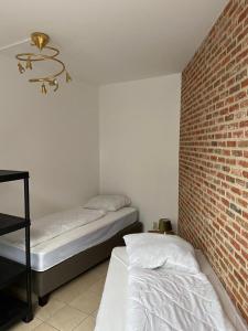 a bedroom with two beds and a brick wall at Apartment de Kerk in Sint-Gillis-Waas