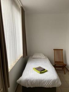 a bed in a room with a window and a chair at Apartment de Kerk in Sint-Gillis-Waas +8 photos