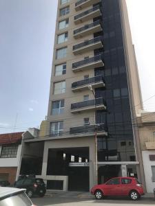 a red car parked in front of a tall building at Espacio Chacabuco in Comodoro Rivadavia