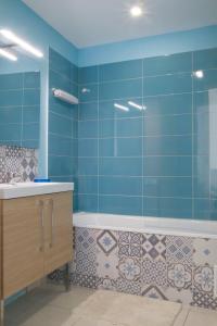 ein blaues Badezimmer mit einer Badewanne und einem Waschbecken in der Unterkunft L'Olympic in Chalezeule