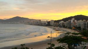 een uitzicht op een strand bij zonsondergang bij Apartamento de Cobertura frente para o mar Itapema in Itapema