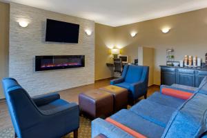 a living room with two blue chairs and a fireplace at Comfort Inn Hobart-Merrillville I-65 in Merrillville