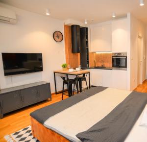 a bedroom with a large bed and a kitchen at Design Apartment near Gorica Park in Podgorica