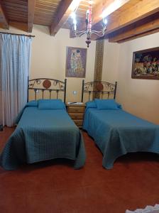 a bedroom with two beds and a chandelier at Casa Rural Marina in Curiel de Duero