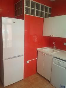 kuchnia z białą lodówką i czerwonymi ścianami w obiekcie Bilbao Cozy Apartment with free Wifi w mieście Bilbao