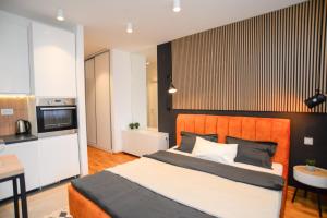 Design Apartment near Gorica Park في بودغوريتسا: غرفة نوم بسرير كبير ومطبخ