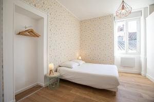 1 dormitorio con cama blanca y ventana en AUDREY-Quartier Mairie-arènes antiques, en Périgueux