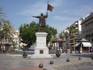 una estatua de un hombre con una bandera en una plaza en Italia 57, en Huelva 2 fotos más