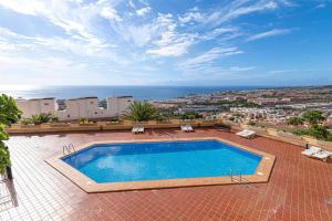 a swimming pool on a patio with a view of the ocean at Top floor with ocean view in Adeje