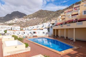 a hotel with a swimming pool in front of buildings at Top floor with ocean view in Adeje