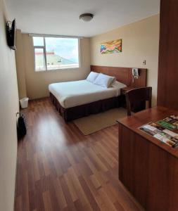 a bedroom with a bed and a desk and a window at Hotel Madrid in La Paz