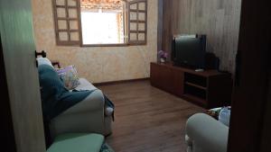 uma sala de estar com um sofá e uma televisão em Sitio Carvalho da Serra em Caeté