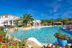 a large swimming pool in a resort with palm trees at Chrousso Village in Paliouri