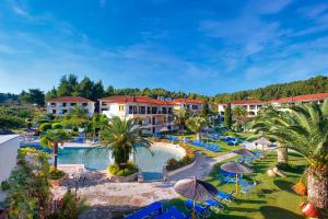 a resort with a large swimming pool and palm trees at Chrousso Village in Paliouri