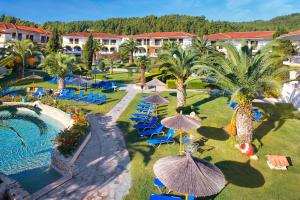 a resort with a pool and chairs and palm trees at Chrousso Village in Paliouri