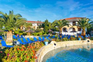 a resort with a pool and chairs and palm trees at Chrousso Village in Paliouri