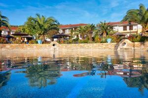 a pool of water with palm trees and buildings at Chrousso Village in Paliouri
