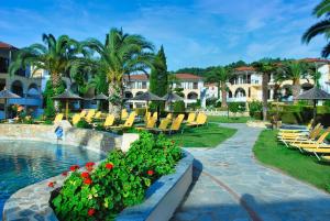 a resort with a pool and chairs and palm trees at Chrousso Village in Paliouri