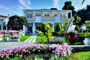 a white house with flowers in front of it at Chrousso Village in Paliouri