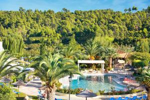 a resort with a pool with palm trees and a mountain at Chrousso Village in Paliouri