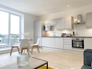 a kitchen with white cabinets and a table and chairs at Fleet Heights Apartment Six in Fleet
