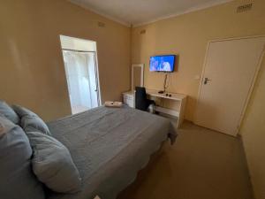 a bedroom with a bed and a tv on the wall at The Hawks Bed and Breakfast in Harare