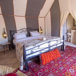 a bedroom with a large bed with a red rug at Berber Soul luxury Camp in Merzouga