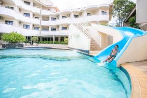 a boy sliding down a slide in a swimming pool at Flat TOP - No Praia Brava Hotel na ilha a beira mar in Florianópolis