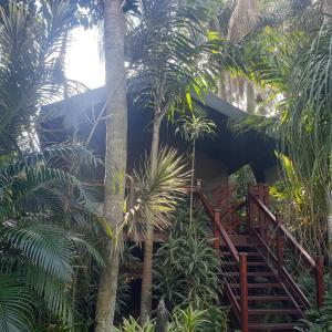 a resort with palm trees and a wooden staircase at Luxury Tented Village @ Urban Glamping in St Lucia