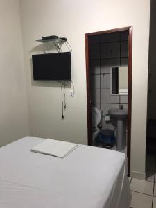 a bedroom with a bed and a bathroom with a sink at Pousadinha- Melhor Localização in Porto Seguro