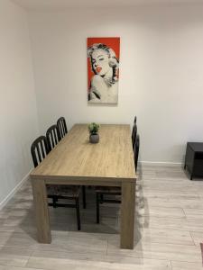 een houten tafel met stoelen en een schilderij aan de muur bij Appartement le Marilyn in La Tour-du-Pin