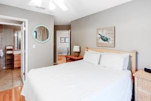 a bedroom with a large white bed and a living room at The Dugout by Meyer Vacation Rentals in Gulf Shores