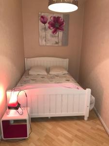 een slaapkamer met een wit bed met een roze bloem aan de muur bij Appartement le Marilyn in La Tour-du-Pin