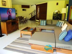 sala de estar con sofá y TV de pantalla plana en Villa Bora Bora - Frente mar, Praia do Forte, en Praia do Forte