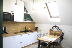 a kitchen with white cabinets and a table with chairs at Danielówka w lesie in Lipka
