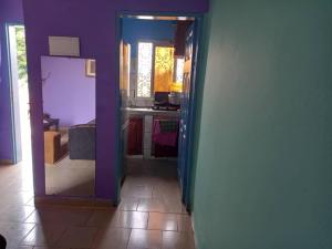 un couloir menant à une cuisine aux murs violets dans l'établissement Résidence Janamaev, à Yaoundé