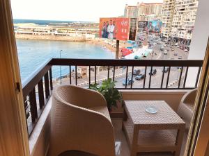 a balcony with chairs and a table and a view of a street at Al Corniche Residence Sea View in Alexandria