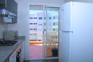a kitchen with a refrigerator and a table with a balcony at Fermer BOUZNIKA Bâtiment C in Bouznika