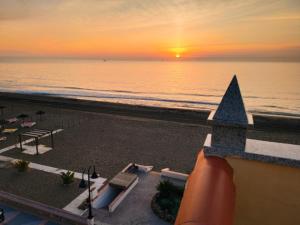 una puesta de sol sobre la playa con un edificio y el océano en Apartamentos Caracas en Torremolinos