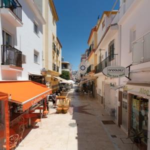 an empty street with a clock on the side of a building at Apartamentos Caracas in Torremolinos