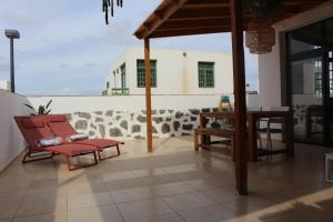 patio z czerwonymi krzesłami i stołem oraz budynek w obiekcie Casa La Esperanza w mieście Playa Blanca