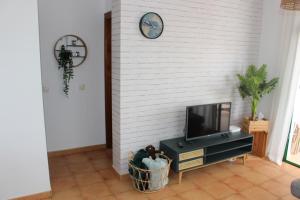 een woonkamer met een tv en een witte bakstenen muur bij Casa La Esperanza in Playa Blanca